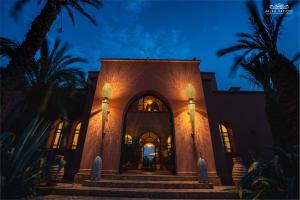 a building with palm trees at night at Palais Hassoun Marrakech in Oulad Snaguia