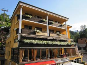 un edificio amarillo con plantas en los balcones en Locanda Seggiovia, en Recoaro Terme