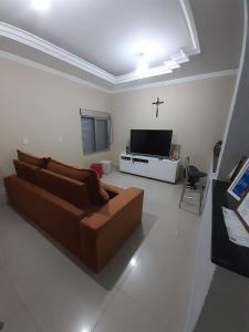 a living room with a brown couch and a tv at Casa Localizado no Centro de Guape MG in Guapé