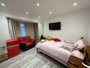 a bedroom with a bed and a chair and a television at Luxury Rooms with En-suite bathrooms - West London in Harrow on the Hill