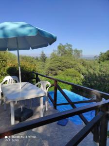 un patio con sombrilla, mesa y sillas en Casas Altas VGB en Villa General Belgrano