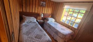 two beds in a room with a window at Cabañas cerca de Valdivia, en San José de la Mariquina in San José de la Mariquina