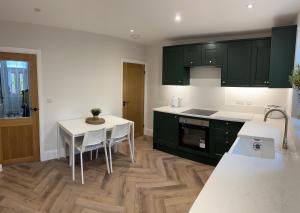 a kitchen with green cabinets and a table with chairs at Ivy Cottage Derbyshire in South Wingfield