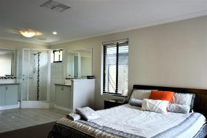 マンジュラにあるMadora Bay Beach Houseのベッドルーム(大型ベッド1台付)、バスルームが備わります。