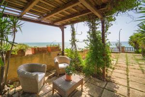 un patio con 2 sillas, una mesa y el océano en Casa Belìce, en Marinella di Selinunte