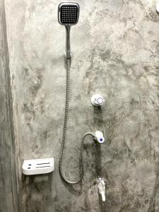 a shower with a hose attached to a wall at Mirana Guest in Weligama