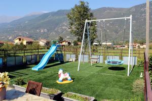 een achtertuin met een speeltuin met een glijbaan en schommels bij Fior di Loto Apartment in Villar Focchiardo