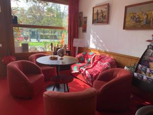 a waiting room with red chairs and a table at HOTEL LES MARRONNIERS in Thonon-les-Bains