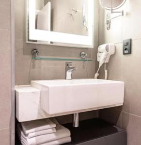 uma casa de banho com um lavatório branco e um espelho. em Studio Alpha Stay One em Barueri
