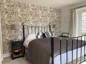 1 dormitorio con cama y papel pintado con motivos florales en Abbey Green Farm en Wem