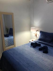 a bedroom with a blue bed with a large mirror at Sandra House Pipa in Pipa