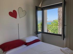 een slaapkamer met een bed en een raam met harten aan de muur bij Eliton in Alghero
