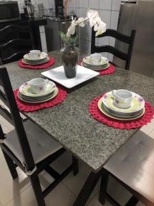 a table with plates and cups and a vase with flowers at Sandra House Pipa in Pipa