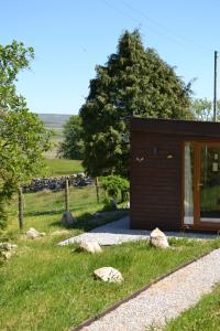 a small cabin in a field with rocks in the grass at The Hive at Ashes Farm in Settle
