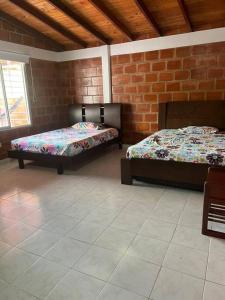 Cette chambre comprend 2 lits et un mur en briques. dans l'établissement Villa Amor - Queremal, à El Queremal