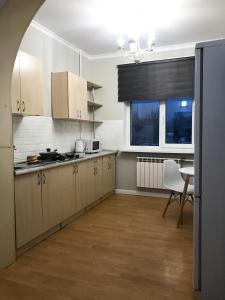 a kitchen with white cabinets and a table and a window at Asaapart Al-Farabi 131/8 in Almaty