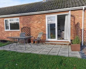 a patio with a table and chairs in front of a brick house at The Annexe in Swanton Morley. in Swanton Morley