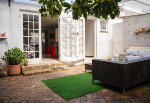 een patio met een bank en een groen tapijt bij Nirvana Cottage in Kaapstad