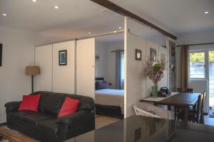 een woonkamer met een bank en een slaapkamer bij Nirvana Cottage in Kaapstad