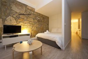a bedroom with a bed and a stone wall at Largo São Domingos by Innapartments in Porto