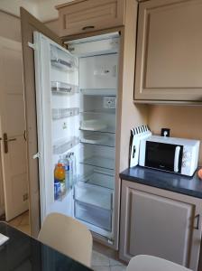 Il comprend une cuisine équipée d'un réfrigérateur ouvert et d'un four micro-ondes. dans l'établissement Grand appartement Athis Mons proche Paris, à Athis-Mons