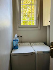 - une bouteille d'eau assise au-dessus d'un lave-linge dans l'établissement Grand appartement Athis Mons proche Paris, à Athis-Mons