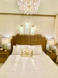a bedroom with a large white bed with a chandelier at RK Maisson Roiyale Pasig in Manila +38 photos