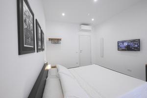Habitación blanca con cama y cuadros en la pared en Signora Titina - Emilia, en Nápoles
