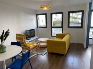 sala de estar con sofá amarillo y sillas en Haut Standing Suresnes, en Suresnes