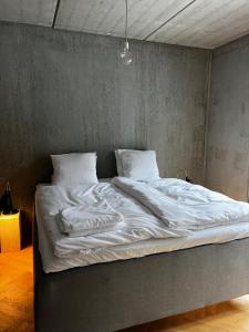 uma cama grande com lençóis brancos e almofadas em Marselisborg Allé 9 B em Arhus