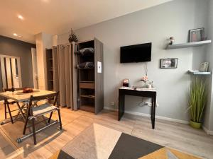 a living room with a table and a television on a wall at Studio tout confort 2 personnes au coeur de l'Alsace in Wolxheim