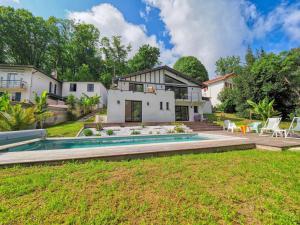 a house with a swimming pool in front of a yard at VILLA MADHUKA - Chambres d'hôtes in Hendaye