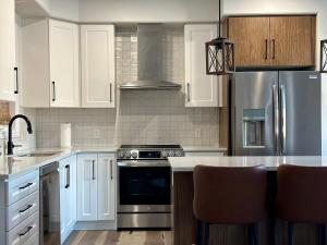 uma cozinha com armários brancos e electrodomésticos de aço inoxidável em Luxury Detached House Kingston em Kingston