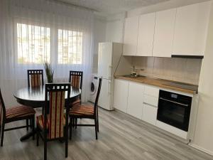 Una cocina con mesa y sillas y un refrigerador. en Best Apartament PR, en Pristina