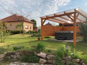 a backyard with a wooden pergola and a grill at Levendula Apartmanház in Gyomaendrőd