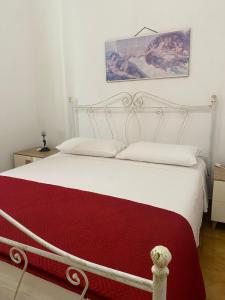 a bedroom with a white bed with a red blanket at CASA ALTOMARE in Otranto