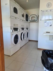 a laundry room with three washing machines and a refrigerator at Depto a orilla del río Calle Calle in Valdivia