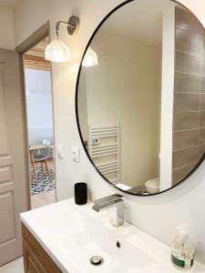 La salle de bains est pourvue d'un grand miroir au-dessus d'un lavabo. dans l'établissement Chalet en Normandie au coeur du pays d'Auge, au Pin