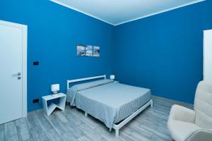 a blue bedroom with a bed and a chair at La Maison Apparthotel in Praia a Mare