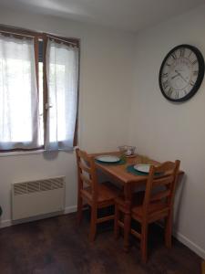 a dining room table with two chairs and a clock on the wall at Studio bleu tout équipé avec wifi in Le Creusot