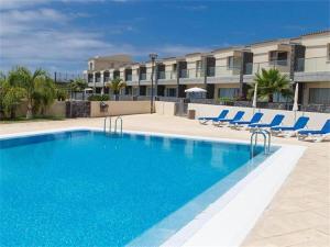 ein Pool mit blauen Stühlen und ein Gebäude in der Unterkunft Amazing Luxury Seafront Villa near Golf & Ocean in San Miguel de Abona
