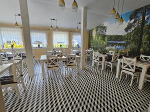 um restaurante com mesas e cadeiras brancas e janelas em Dolcevita Podlasie em Bondary
