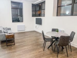Swindon City Centre Apartments by Elegance Living في سويندون: غرفة معيشة مع طاولة وكراسي وأريكة