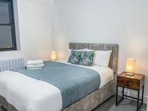 斯溫頓的住宿－Swindon City Centre Apartments by Elegance Living，一间卧室配有一张床和一张带两盏灯的桌子。
