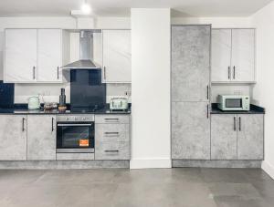 Swindon City Centre Apartments by Elegance Living في سويندون: مطبخ مع دواليب بيضاء وميكرويف