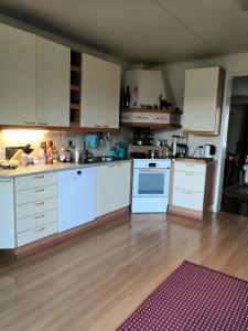 a kitchen with white cabinets and a wooden floor at Homestay cozy hosting in Tervakoski