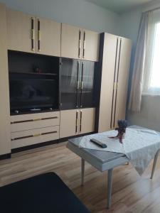 uma sala de estar com uma televisão, uma mesa e um frigorífico em Sweet Home Appartman em Kazincbarcika