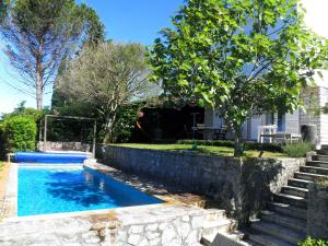 een zwembad met een stenen muur naast een huis bij Holiday Home Valica in Malinska