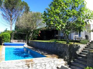 a swimming pool with a stone retaining wall next to a house at Holiday Home Valica in Malinska