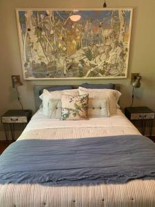 a bedroom with a bed with a large painting on the wall at Gingerbird Art Suite in Laurel